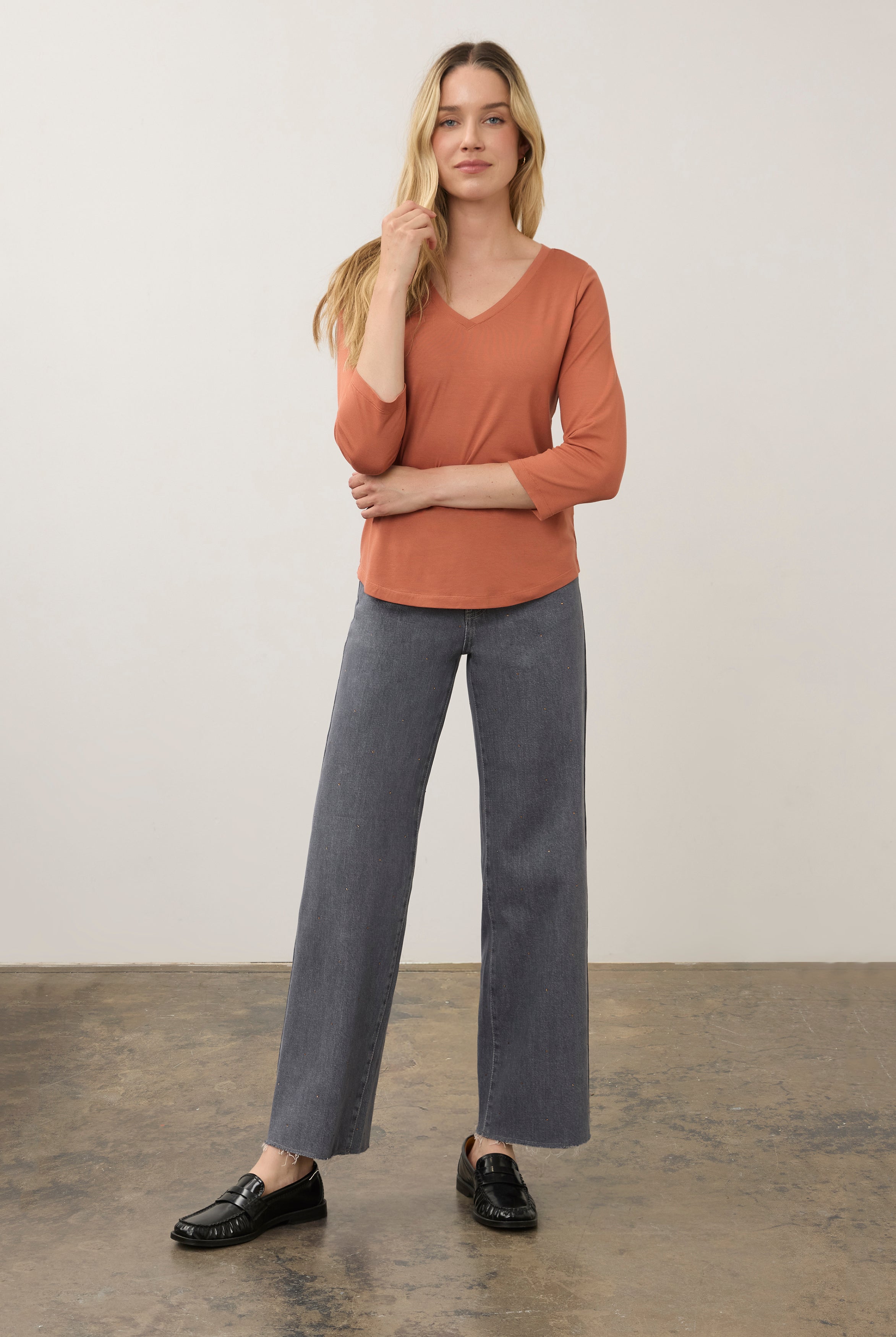 Full body view of orange V-neck top paired with gray pants for a modern look by French Dressing Jeans (FDJ)