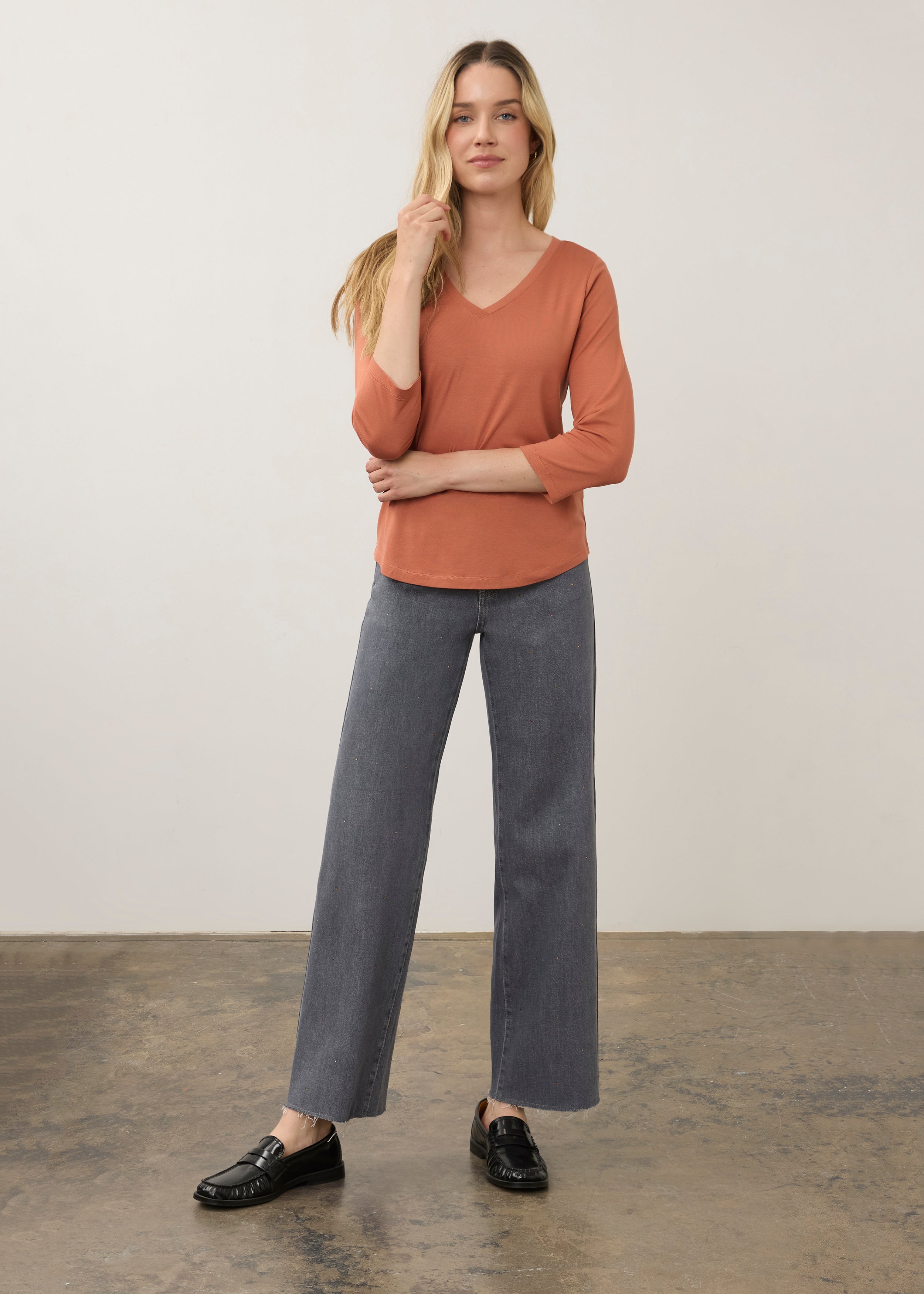 Full body view of orange V-neck top paired with gray pants for a modern look by French Dressing Jeans (FDJ)