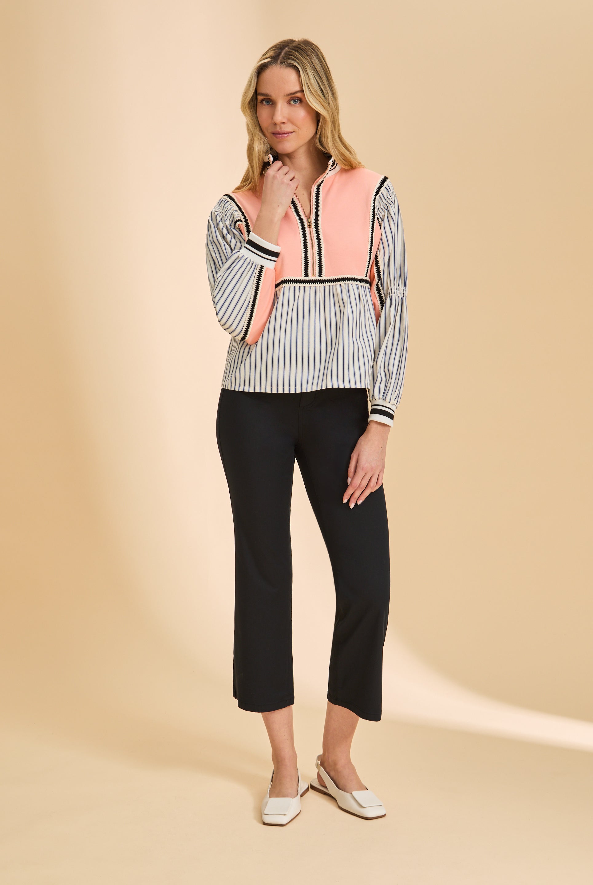 Full body shot of cantaloupe half zip top with striped pattern and black pants by French Dressing Jeans (FDJ)