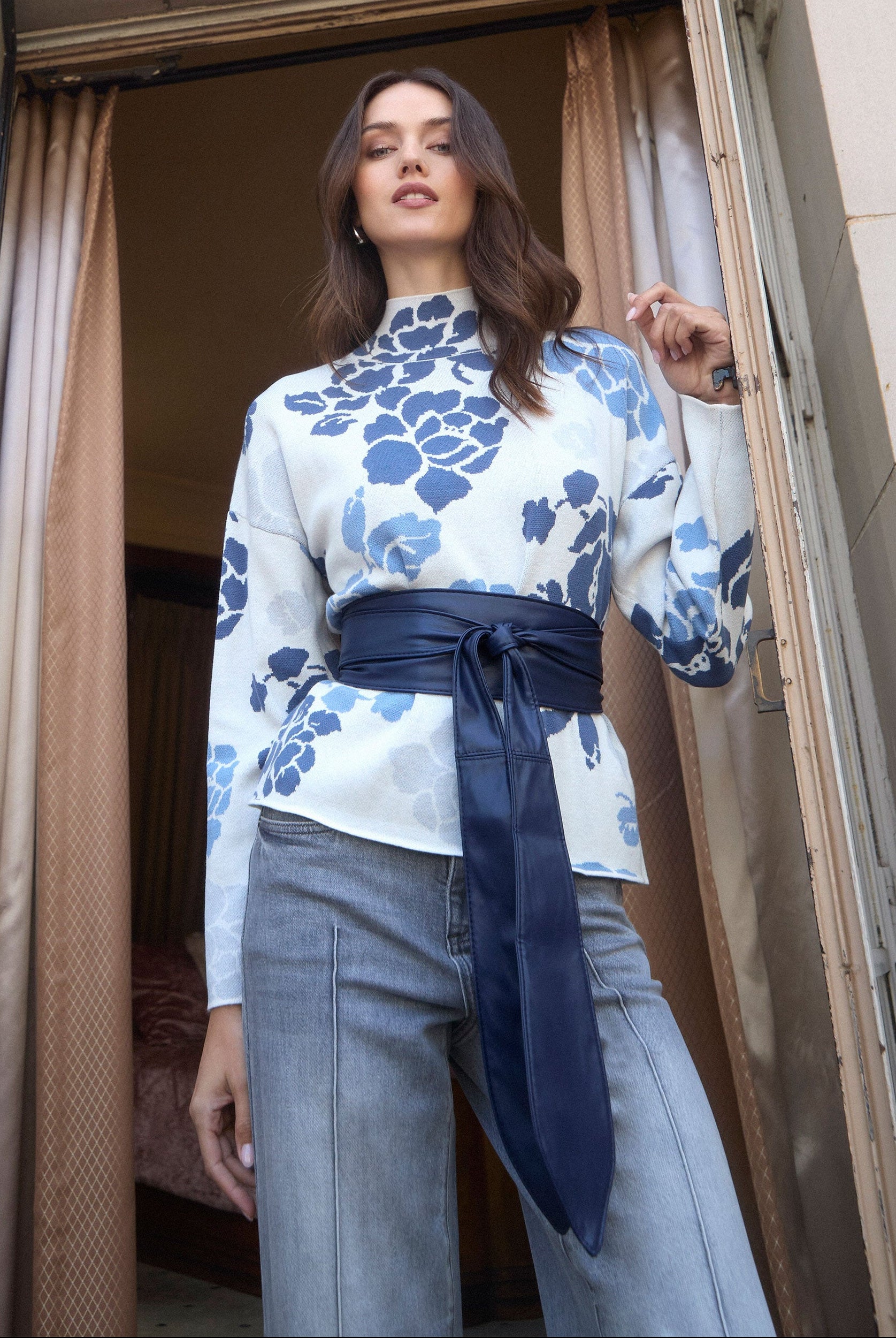 Model wearing floral printed sweater with blue and white patterns, posing by French Dressing Jeans (FDJ)