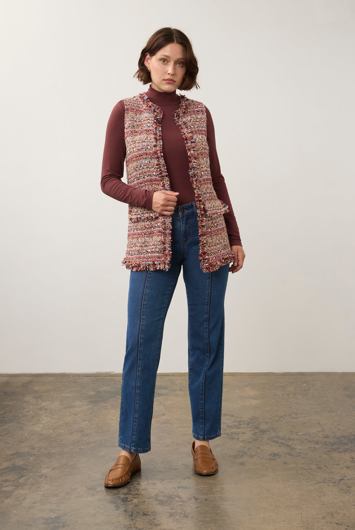 Full-body shot of model in multicolored textured vest paired with blue jeans by French Dressing Jeans (FDJ)