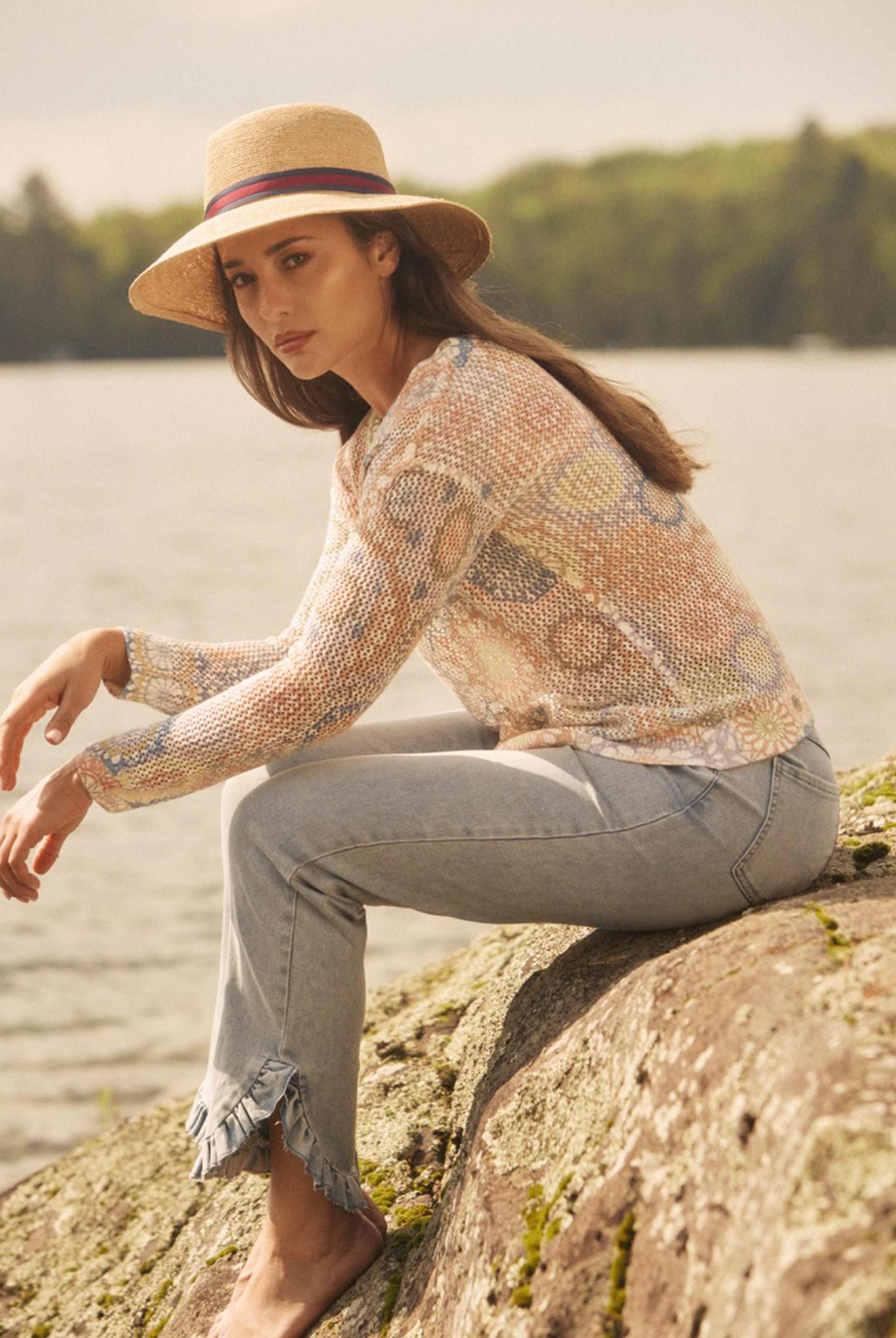 Side view of model seated on rocks wearing pull-on boot crop denim with frayed edges by French Dressing Jeans (FDJ)