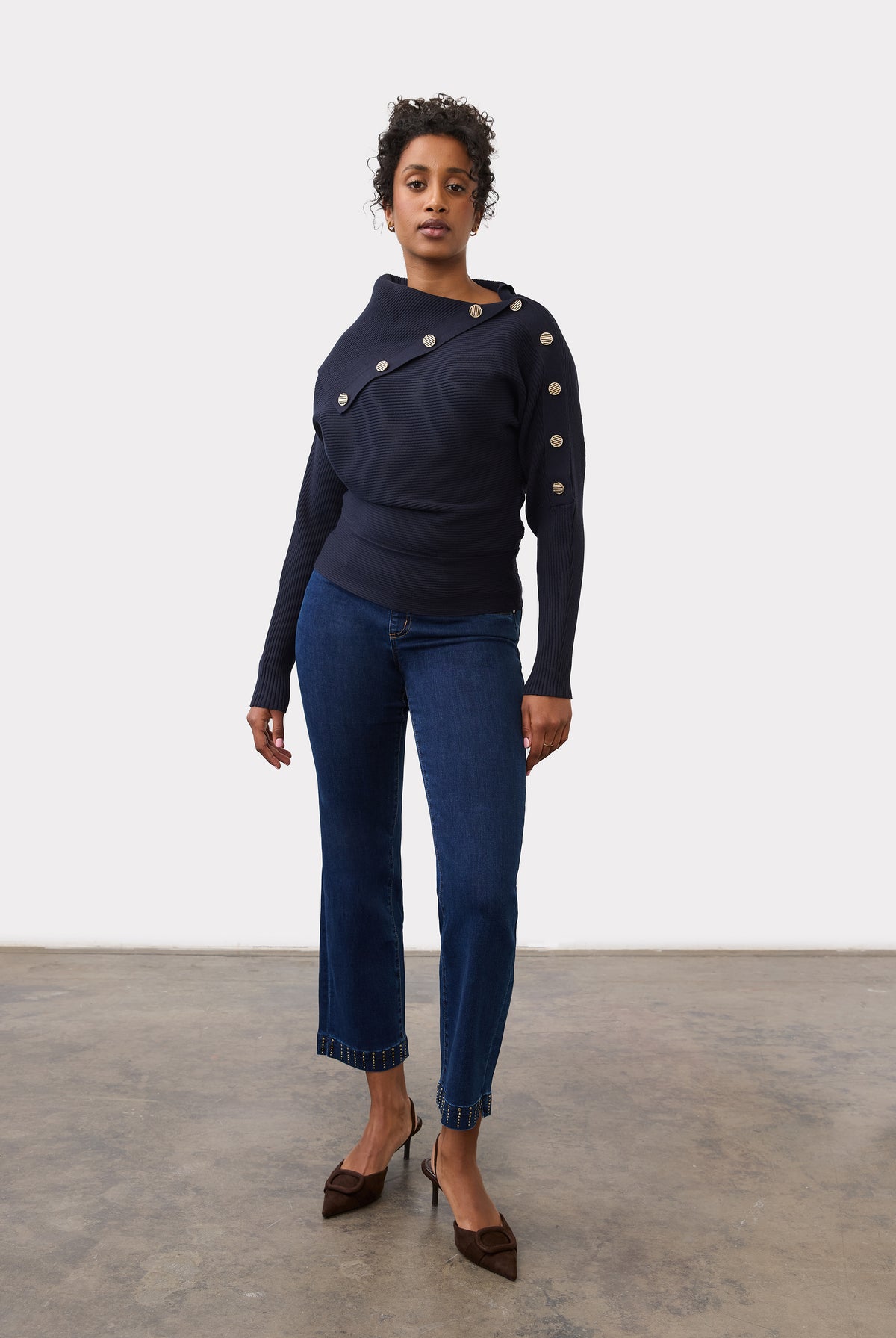 Full-length view of model in navy sweater with button details and blue jeans by French Dressing Jeans (FDJ)