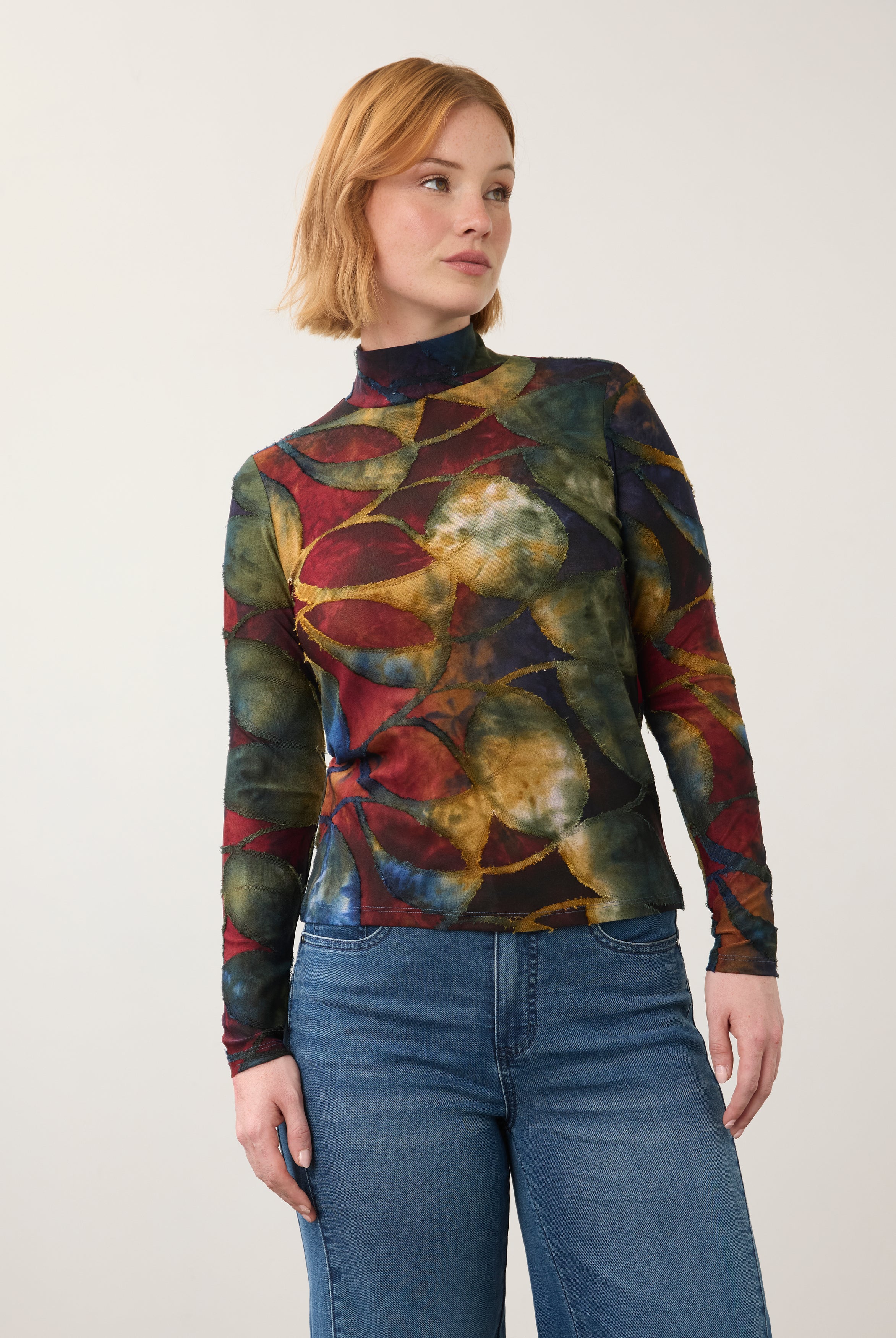 Front view of abstract print top in deep hues, paired with denim jeans by French Dressing Jeans (FDJ)