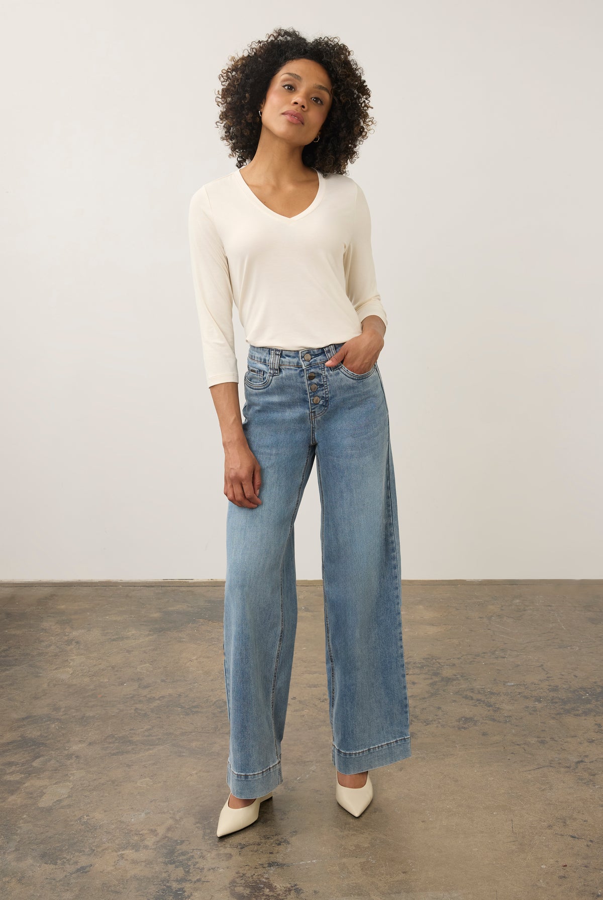 Full body view of cream V-neck top with relaxed fit and paired with high-waist jeans by French Dressing Jeans (FDJ)