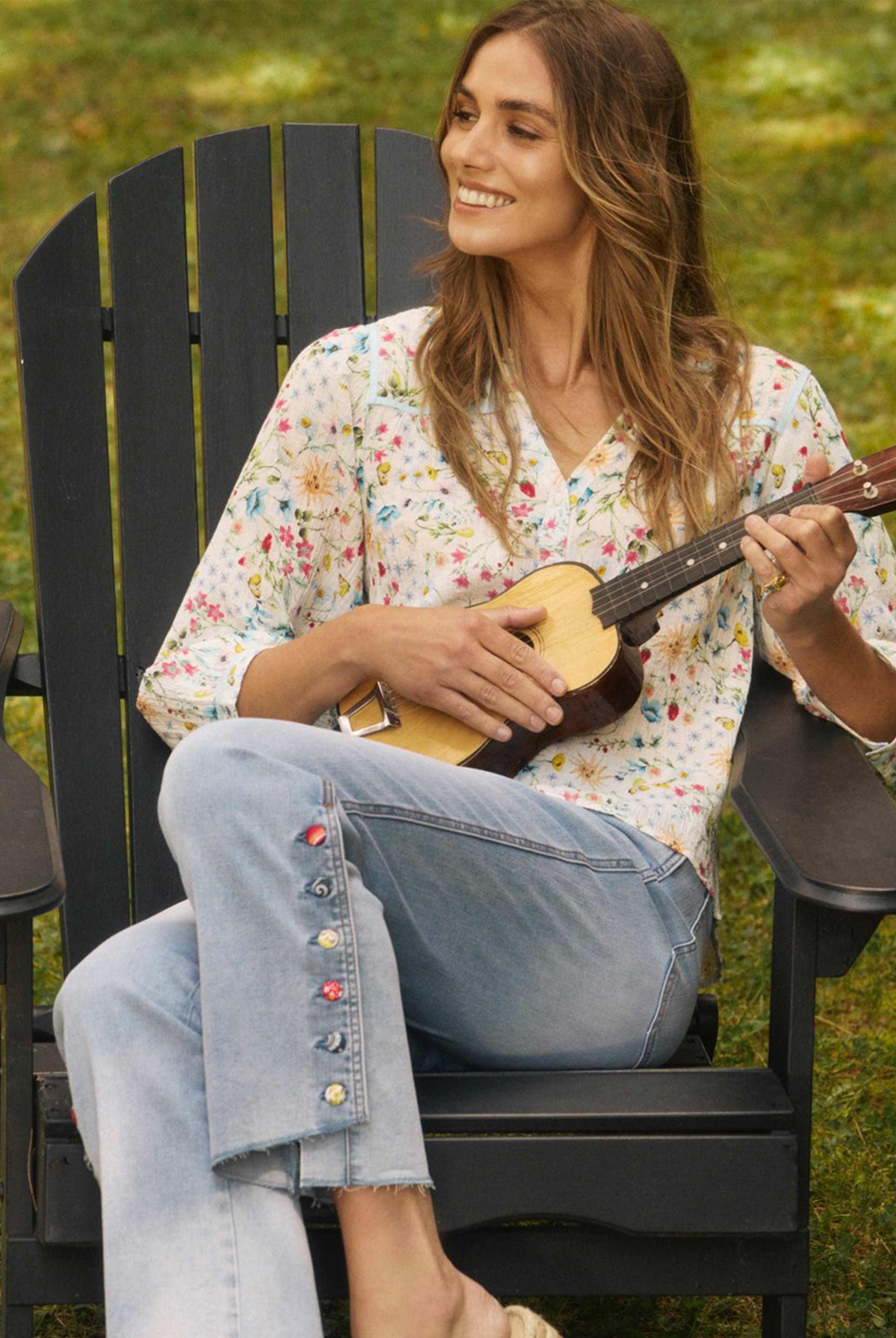 Model sitting, wearing blue eclipse pull-on boot crop denim with decorative buttons by French Dressing Jeans (FDJ)