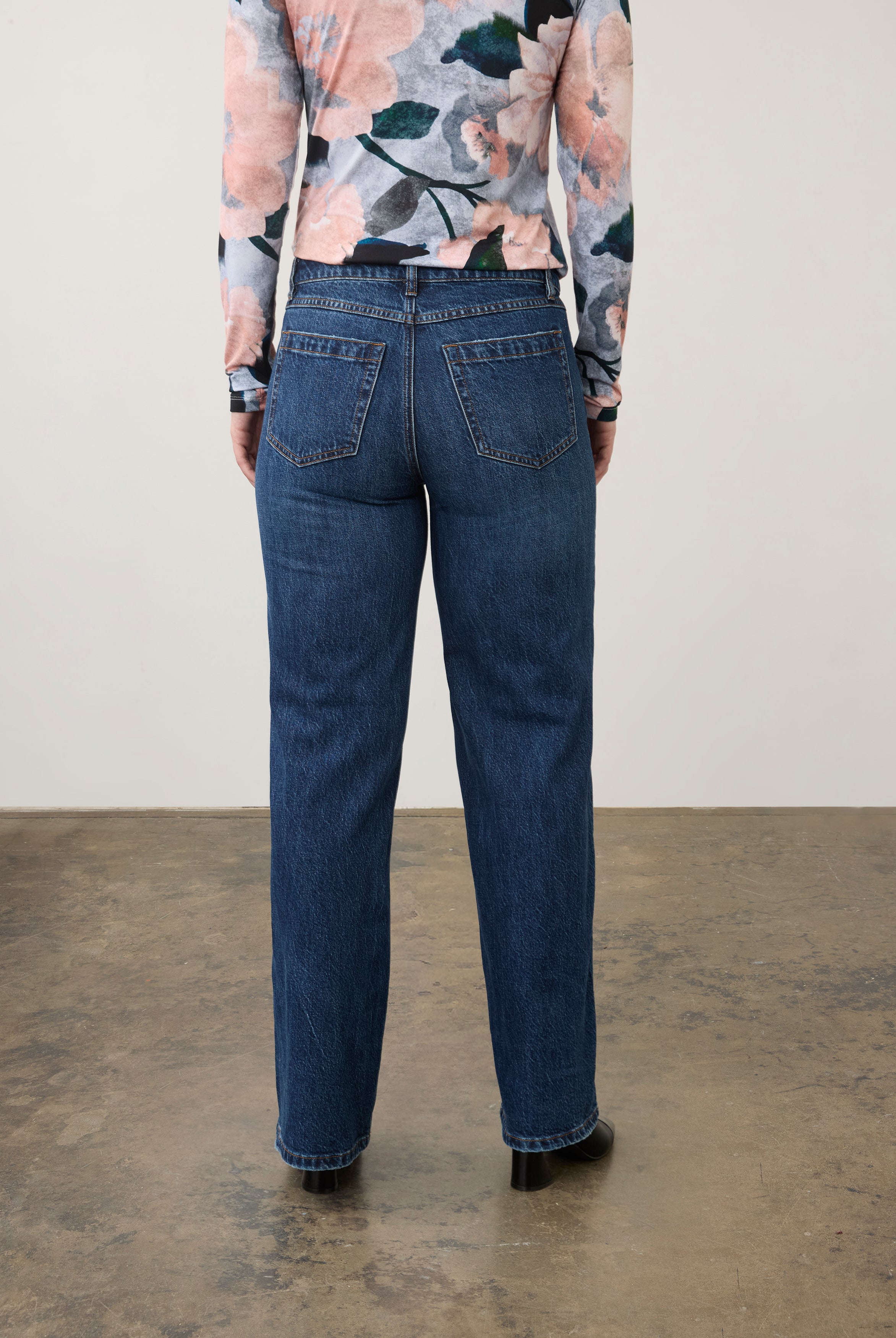 Back view of dark wash jeans with floral top, showcasing back patch pockets by French Dressing Jeans (FDJ) par French Dressing Jeans (FDJ)
