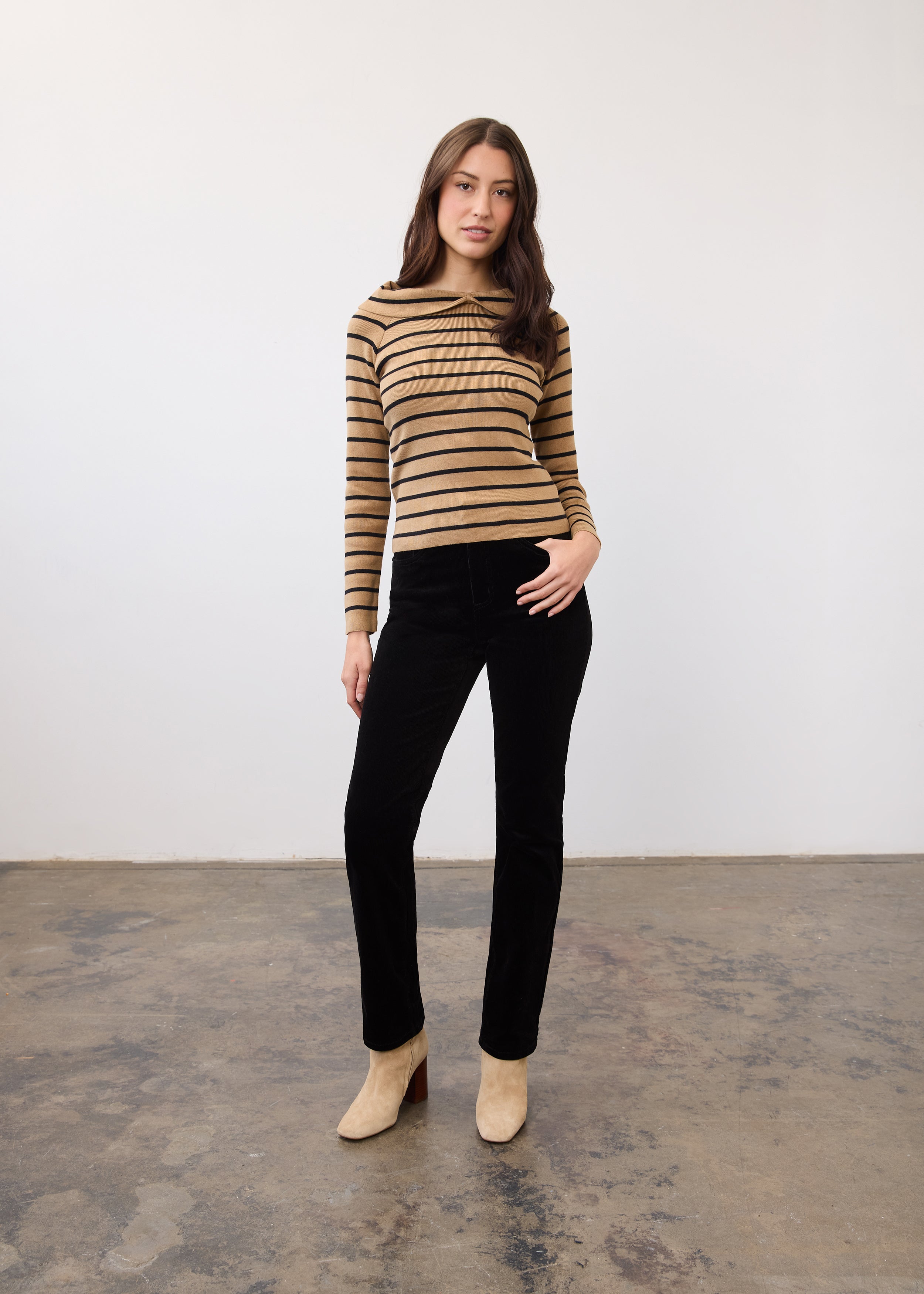 Full body view of striped tan and black sweater paired with black pants by French Dressing Jeans (FDJ)