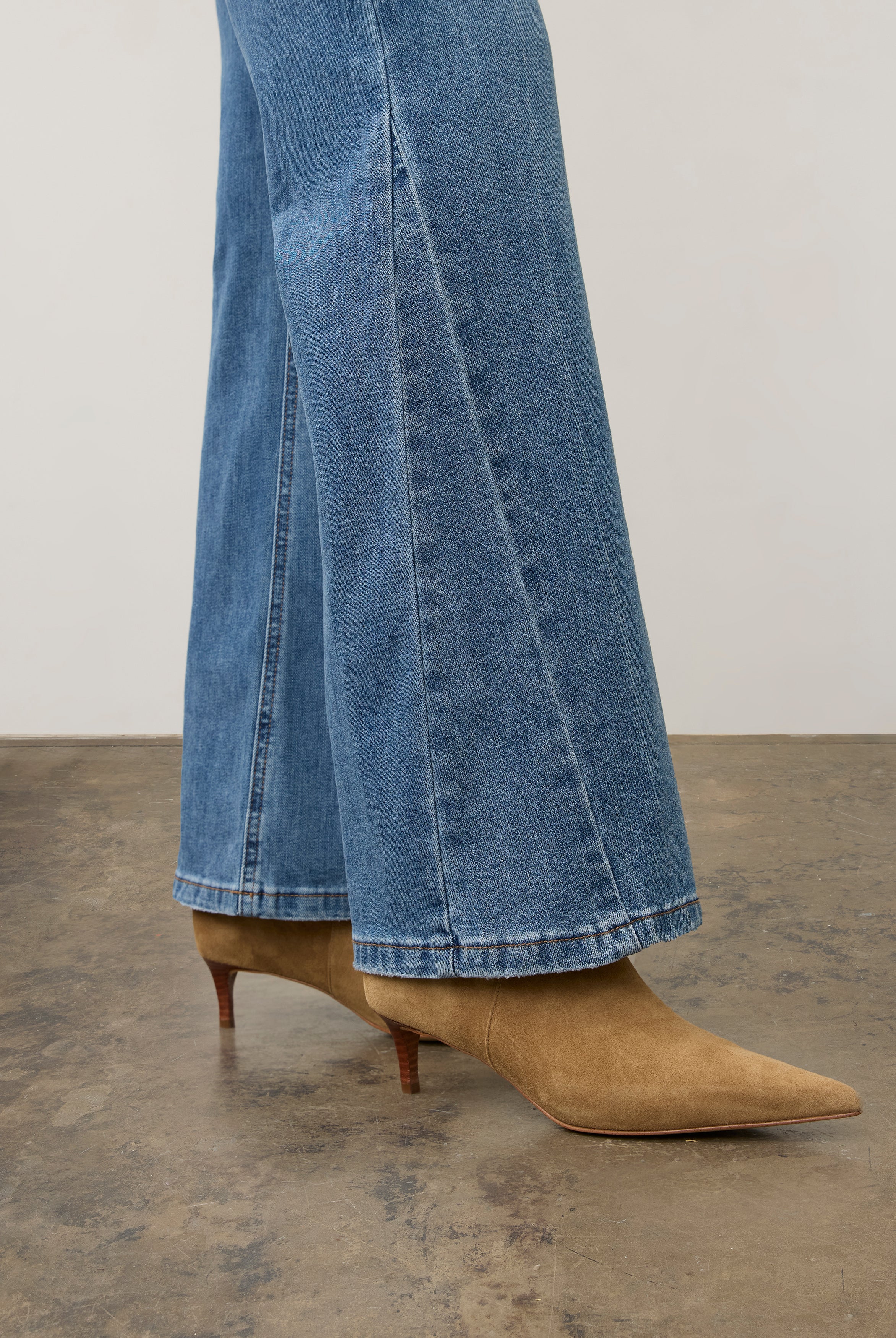 Side view of medium wash denim pants highlighting bootcut design and hem details by French Dressing Jeans (FDJ) par French Dressing Jeans (FDJ)