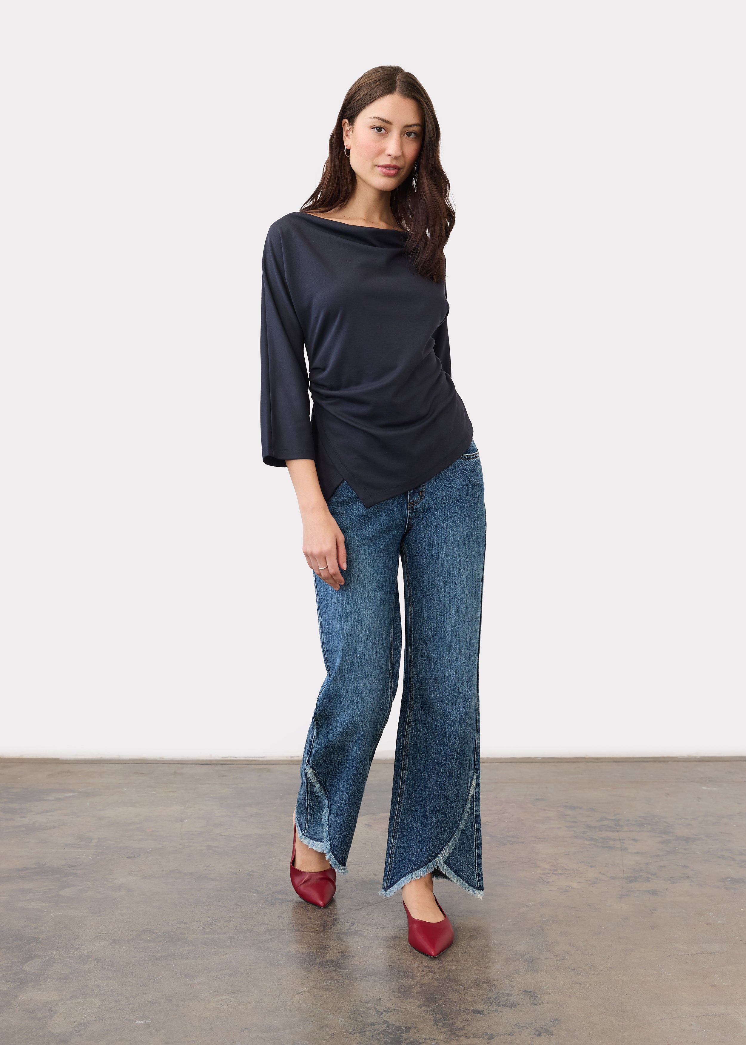 Full view of model wearing medium blue bootleg jeans with tulip hem by French Dressing Jeans (FDJ)