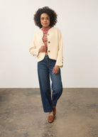 Full-body shot of model in cream knit cardigan paired with blue jeans by French Dressing Jeans (FDJ)