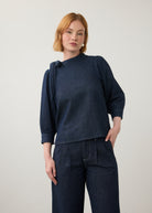Front view of dark wash puff-sleeve top with wide-leg pants showing pleated waist by French Dressing Jeans (FDJ)