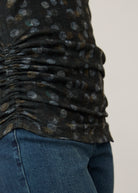Side detail of ruched hem on black polka dot top, paired with denim jeans by French Dressing Jeans (FDJ)
