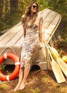Outdoor shot of woman in printed dress sitting on boat, showcasing casual style by French Dressing Jeans (FDJ)