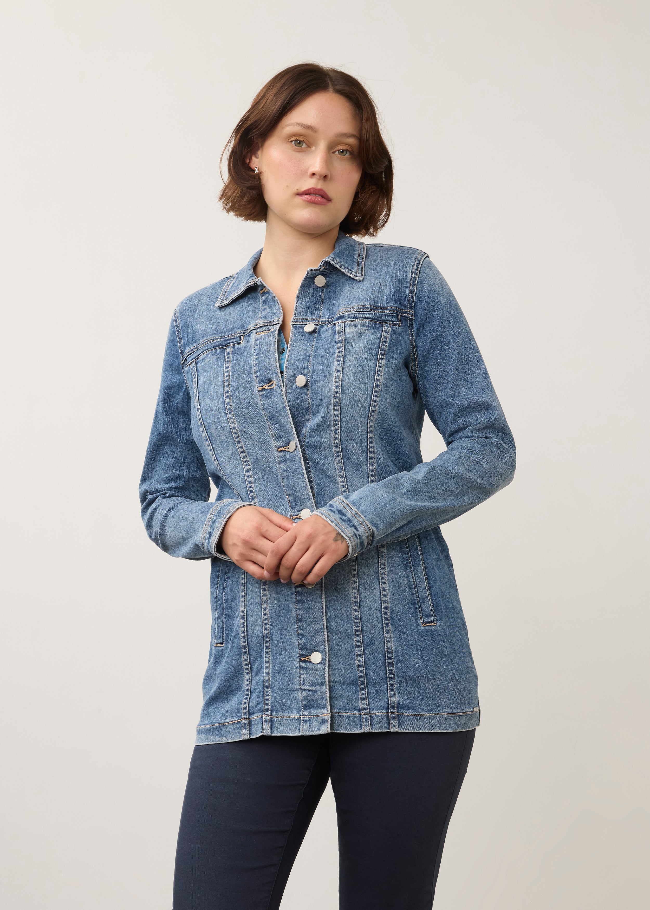 Front view of long denim jacket in medium wash with button closure and side seam pockets by French Dressing Jeans (FDJ) par French Dressing Jeans (FDJ)