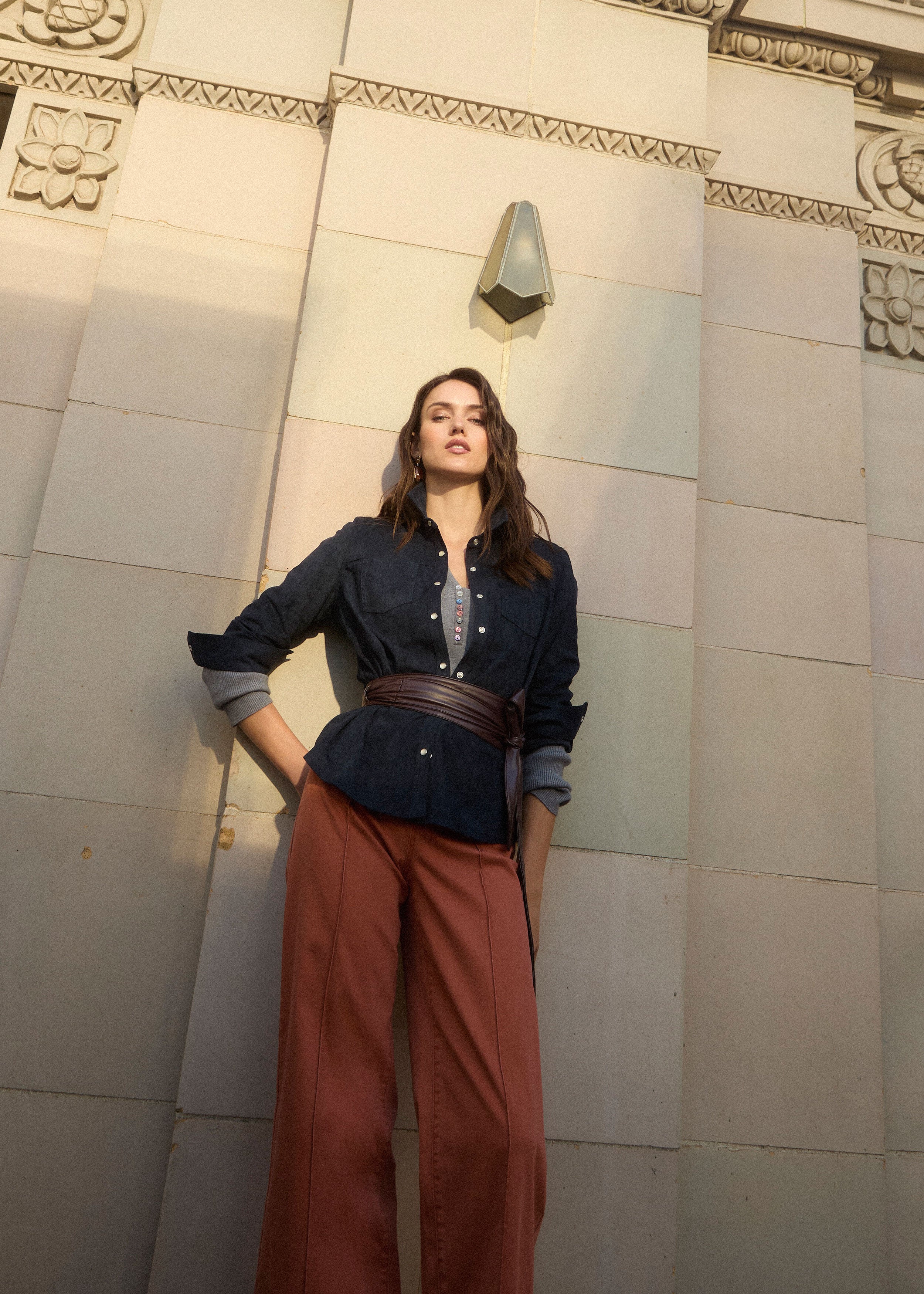Outdoor shot of model in terracotta wide-leg denim under architectural backdrop by French Dressing Jeans (FDJ) par French Dressing Jeans (FDJ)