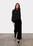 Full view of model wearing black Olivia wide leg pants paired with a black top by French Dressing Jeans (FDJ)