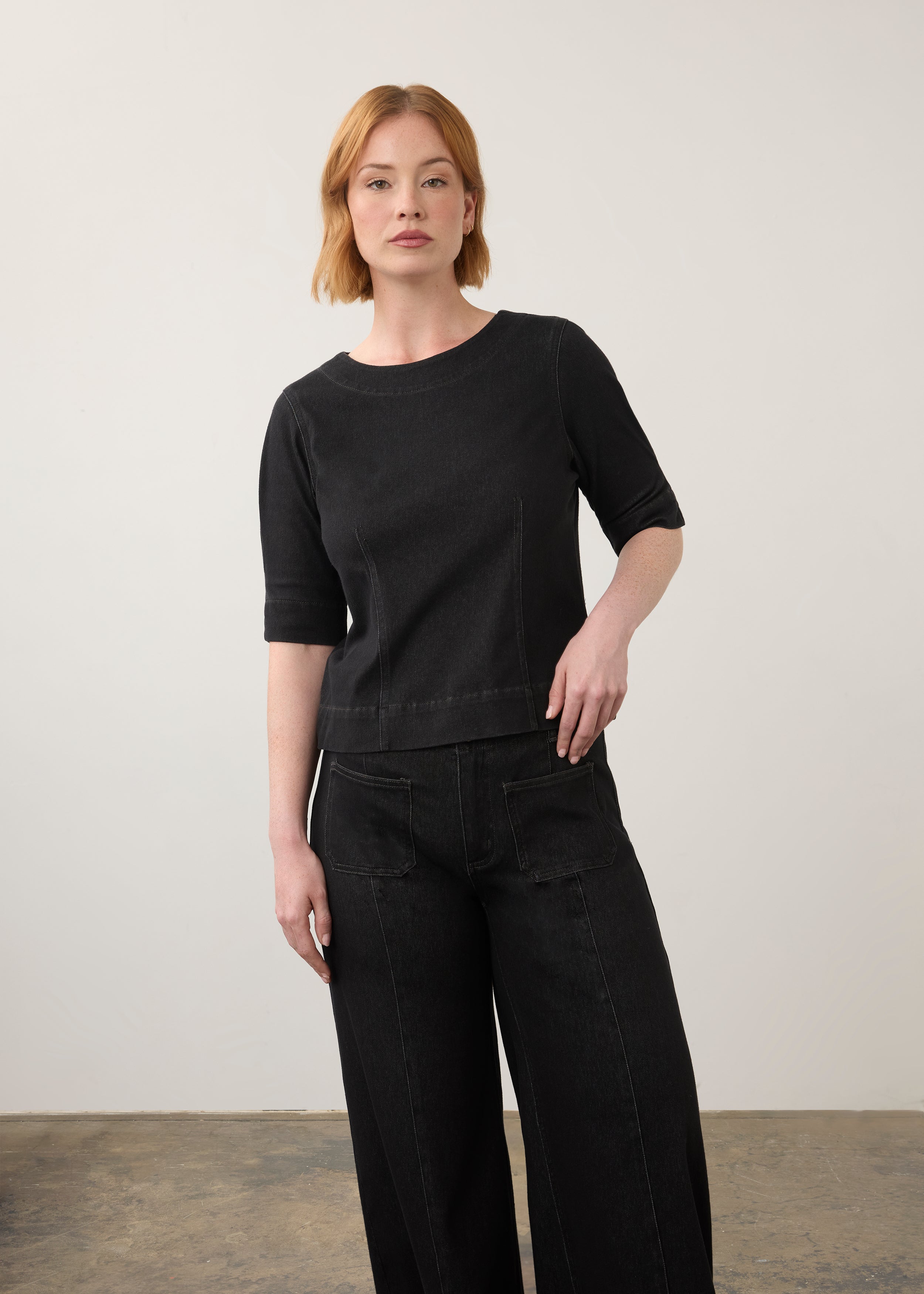 Black fitted top with elbow-length sleeves paired with wide-leg jeans by French Dressing Jeans (FDJ)