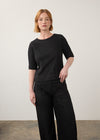 Black fitted top with elbow-length sleeves paired with wide-leg jeans by French Dressing Jeans (FDJ)