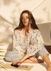 Model seated wearing Ambush Floral blouse, showcasing vibrant print and relaxed fit by French Dressing Jeans (FDJ)