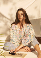 Model seated wearing Ambush Floral blouse, showcasing vibrant print and relaxed fit by French Dressing Jeans (FDJ)