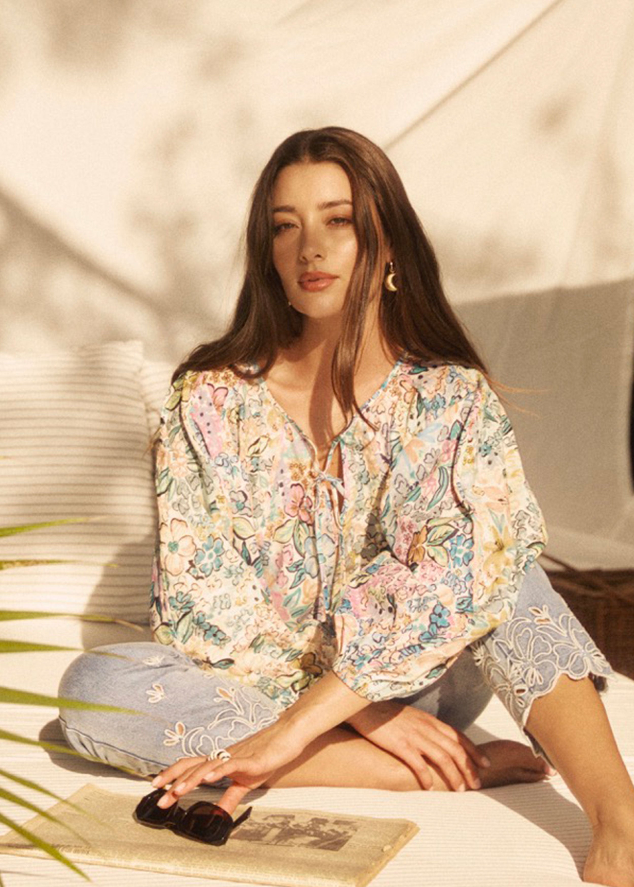 Model seated wearing Ambush Floral blouse, showcasing vibrant print and relaxed fit by French Dressing Jeans (FDJ)