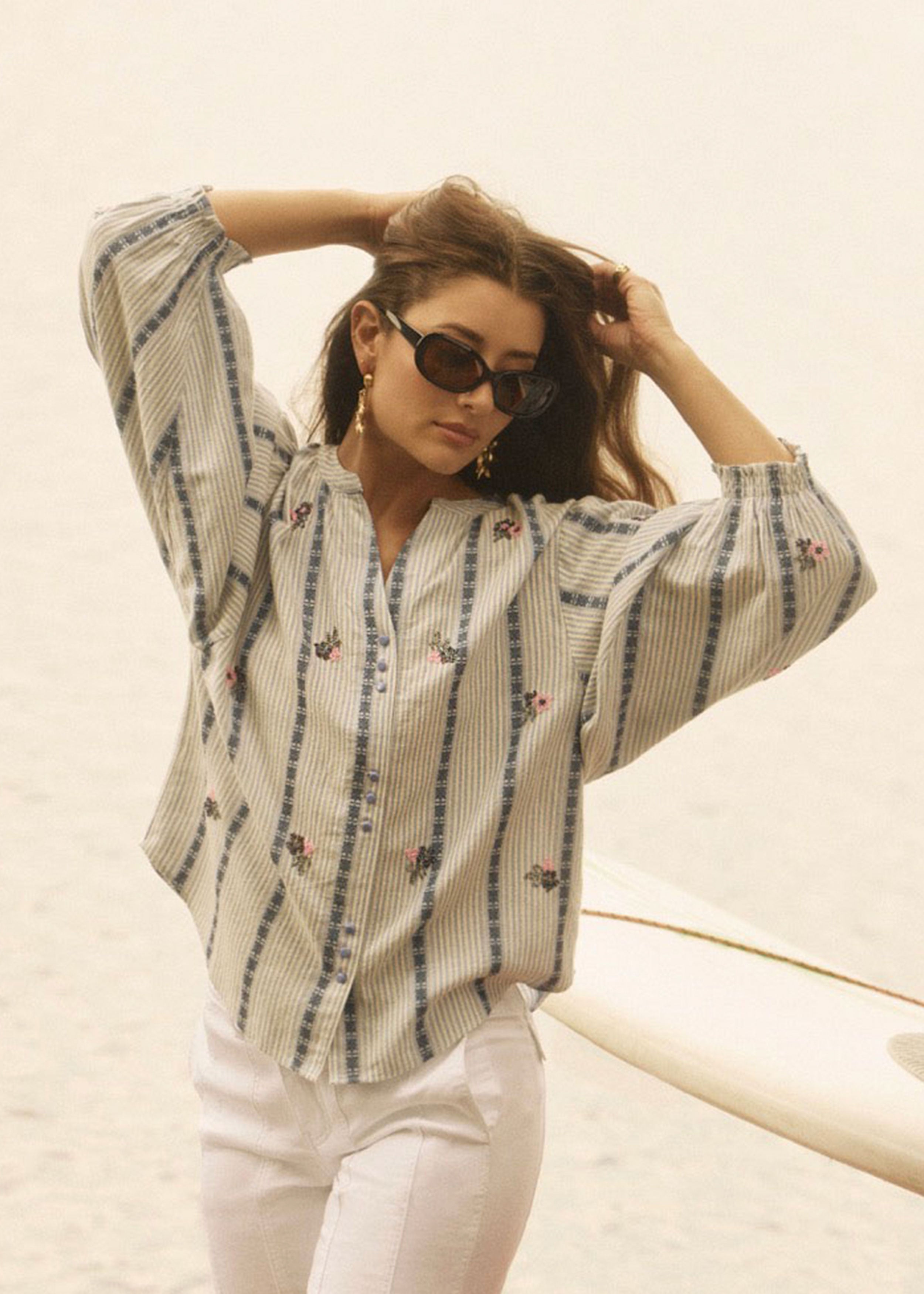 Outdoor view of woman in striped shirt with floral accents and sunglasses by French Dressing Jeans (FDJ)