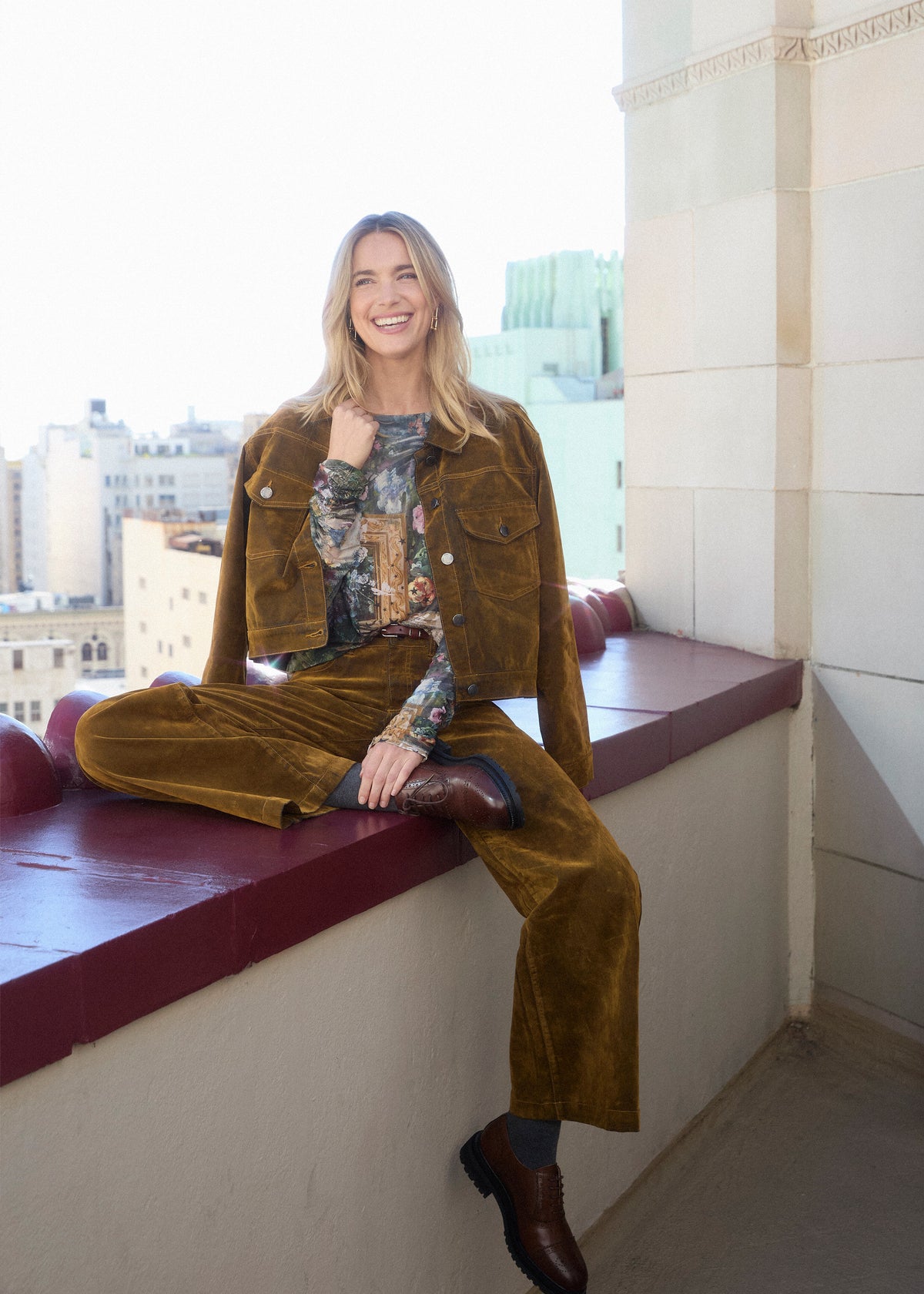 Model seated on a ledge wearing brass Olivia wide leg denim with matching jacket by French Dressing Jeans (FDJ)