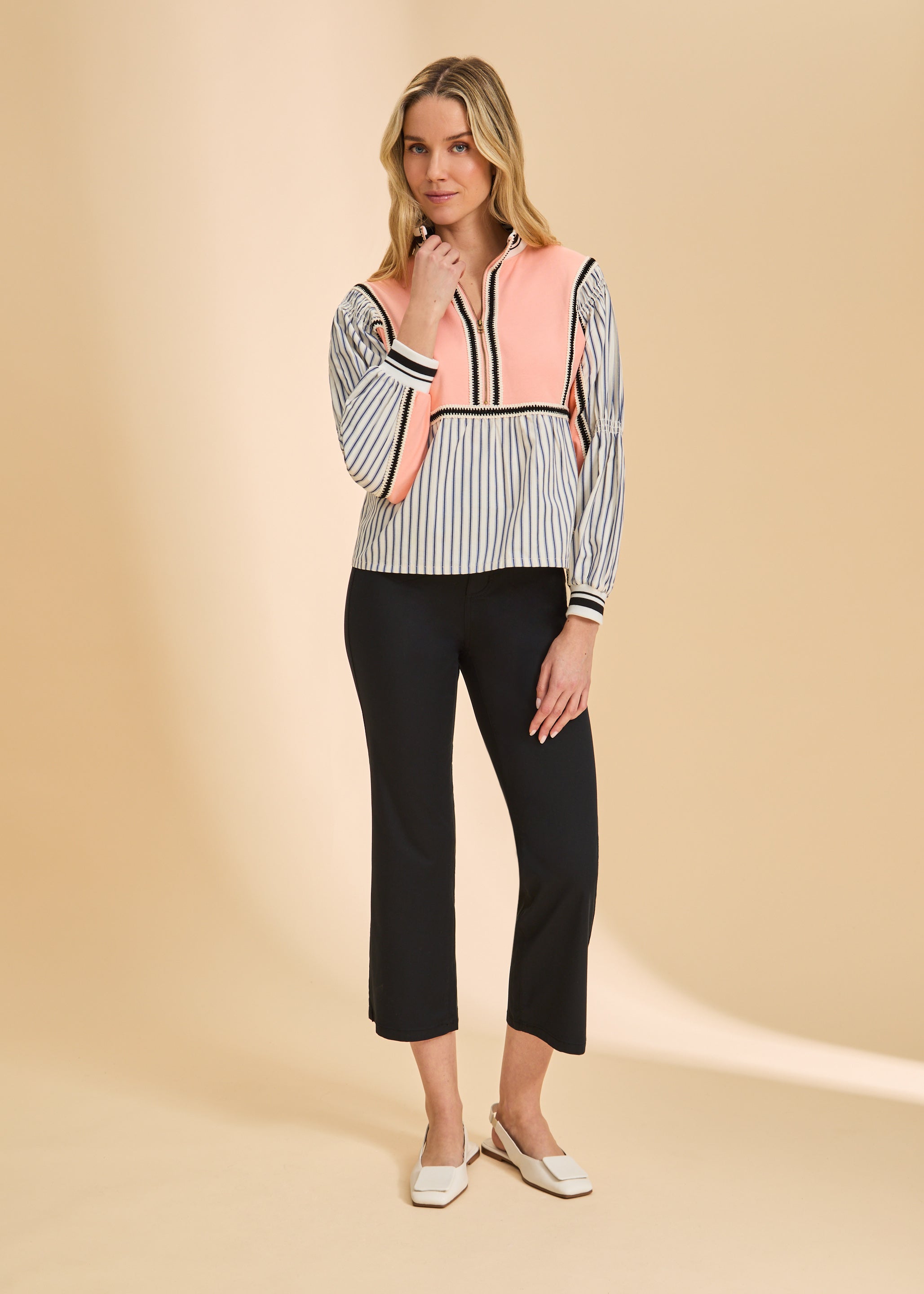 Full body shot of cantaloupe half zip top with striped pattern and black pants by French Dressing Jeans (FDJ)
