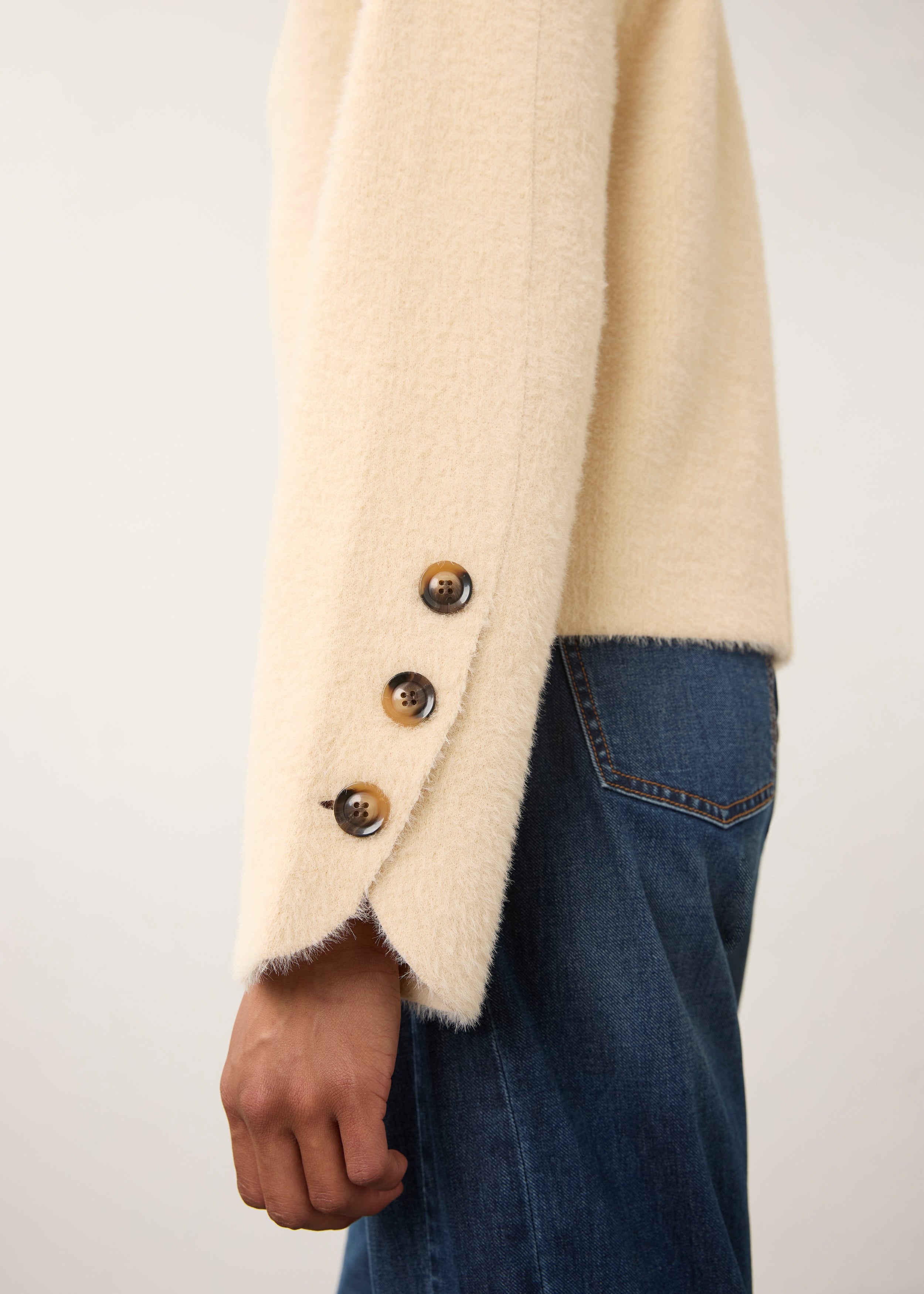 Side view of cream knit cardigan emphasizing buttoned sleeve detail by French Dressing Jeans (FDJ)