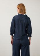 Back view of dark wash puff-sleeve top with buttoned cuffs and pleated back detail by French Dressing Jeans (FDJ)