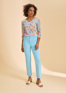 Full-body view of model wearing abstract print V-neck top with blue jeans by French Dressing Jeans (FDJ)