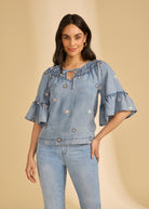 Front view of denim top with floral embroidery and ruffled neckline by French Dressing Jeans (FDJ)