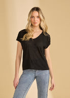 Front view of black V-neck top with crochet shoulder details paired with jeans by French Dressing Jeans (FDJ)