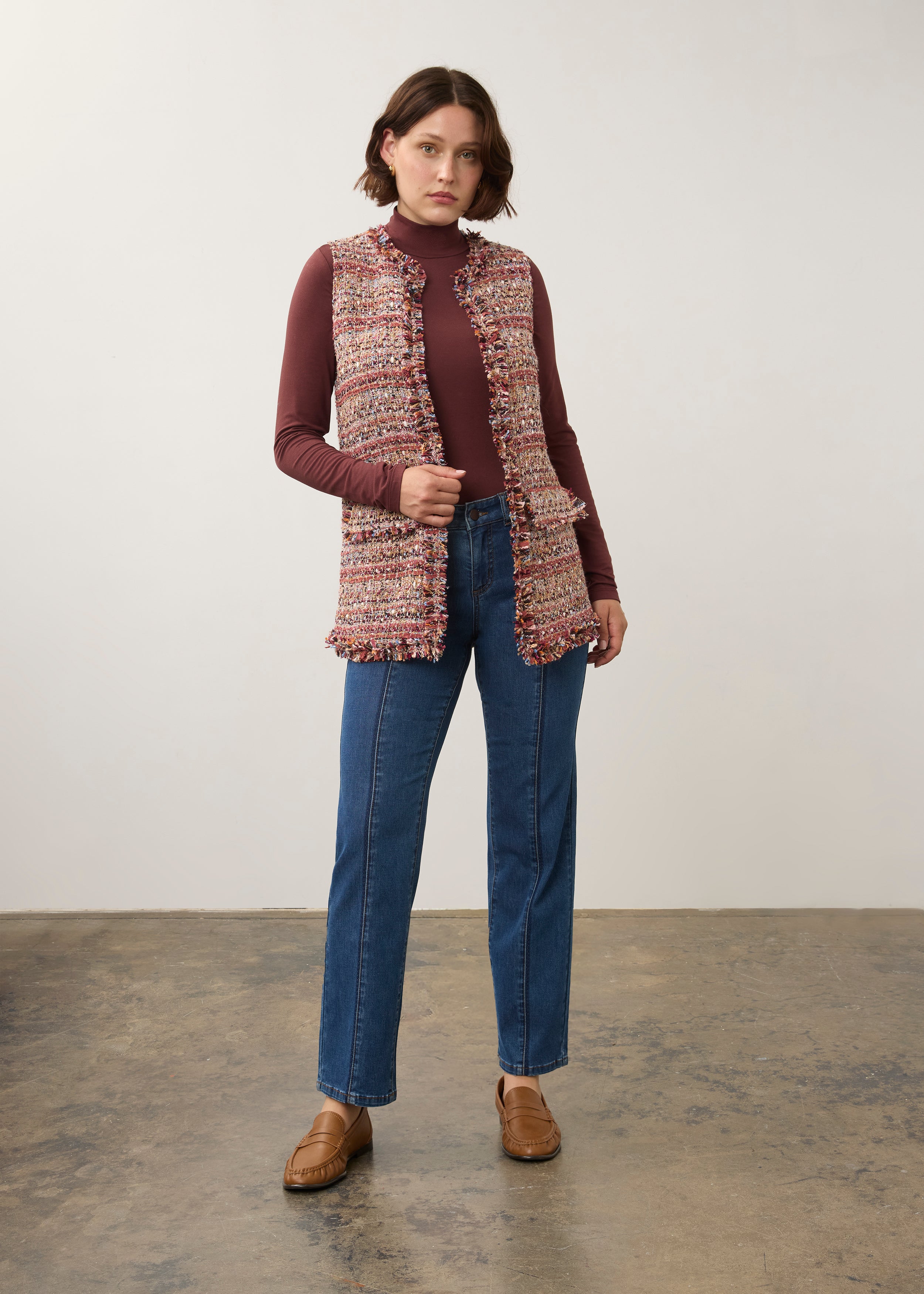 Full-body shot of model in multicolored textured vest paired with blue jeans by French Dressing Jeans (FDJ)