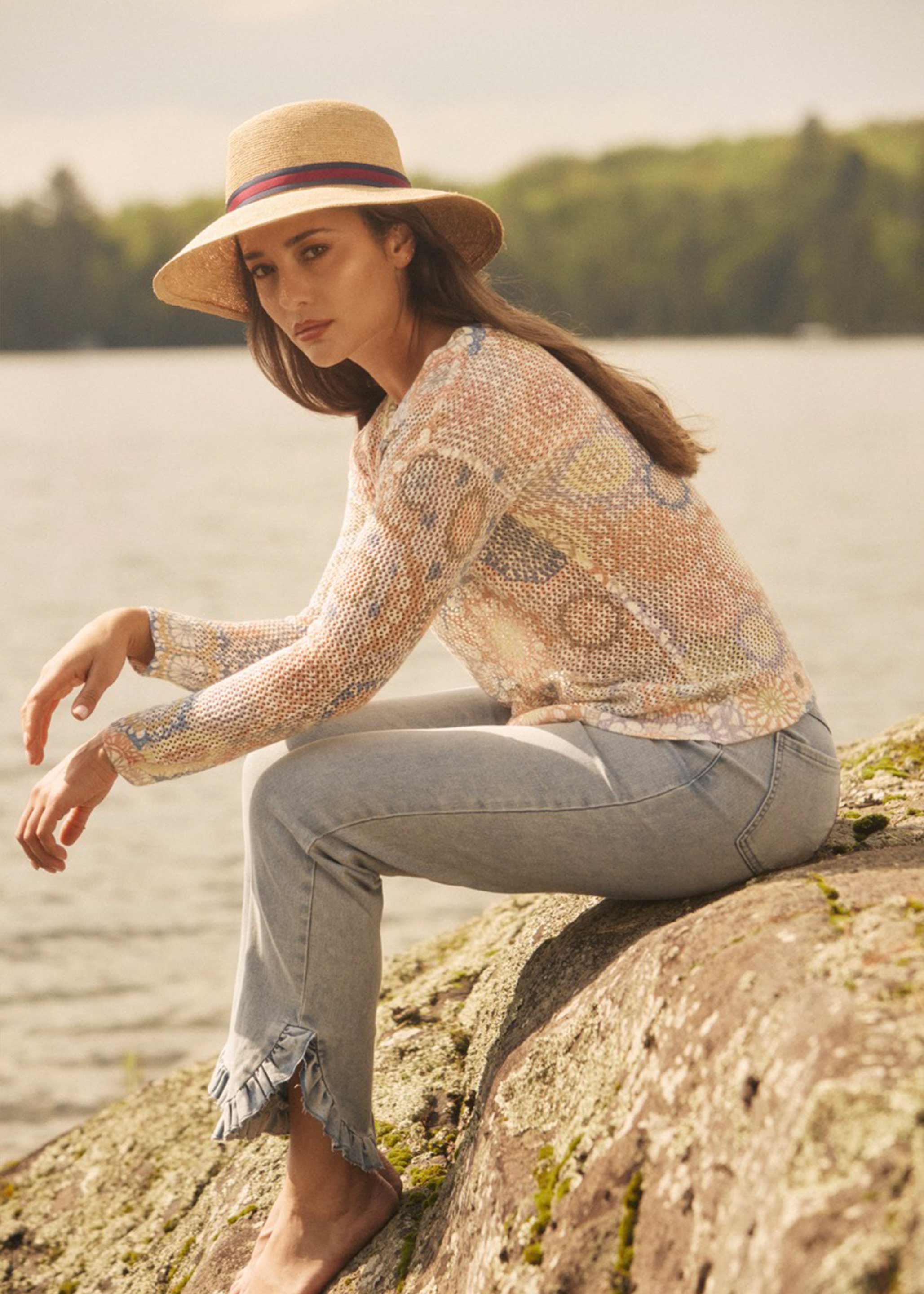 Side view of model seated on rocks wearing pull-on boot crop denim with frayed edges by French Dressing Jeans (FDJ)