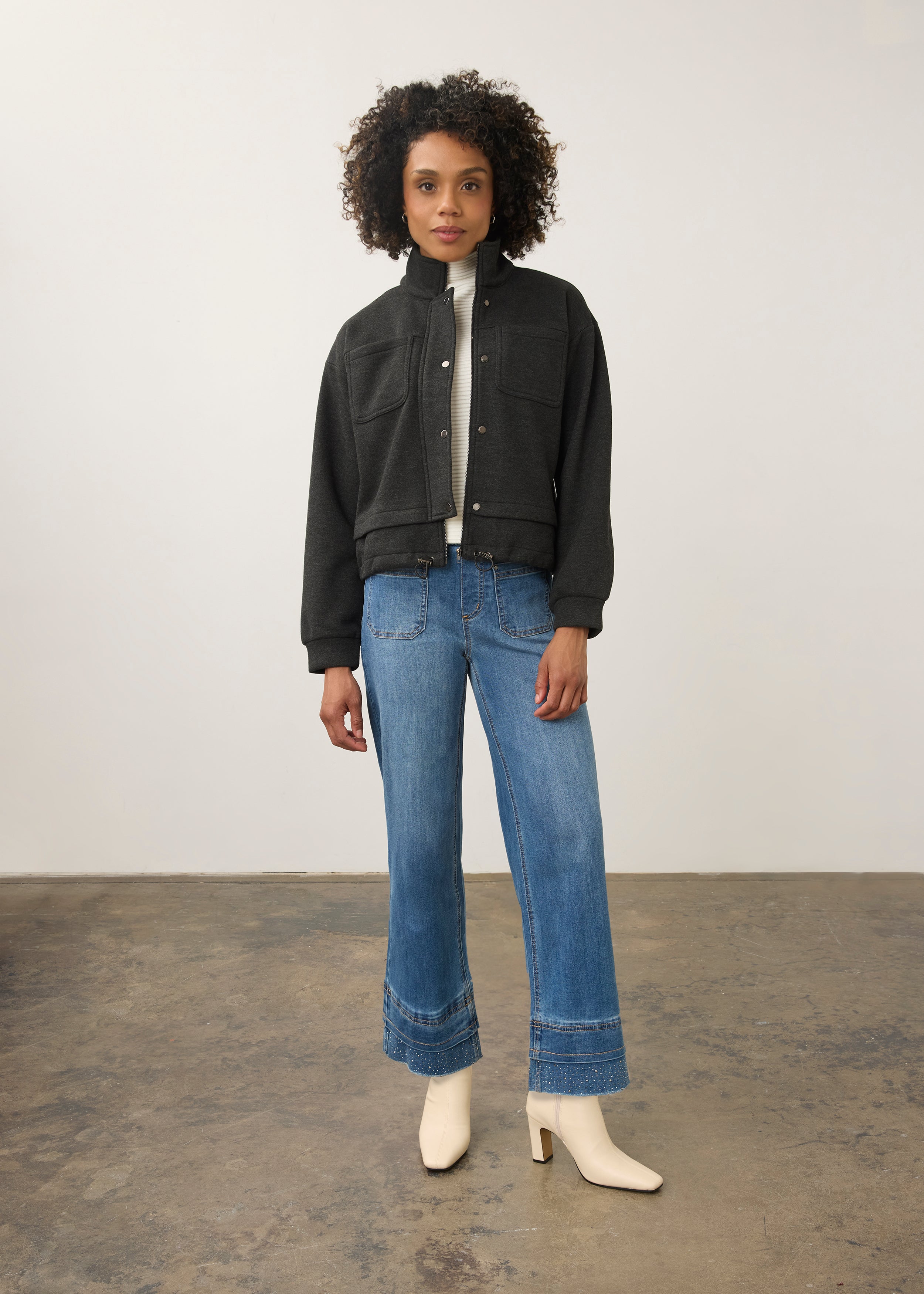 Full-body shot of model in charcoal knit bomber jacket paired with blue jeans by French Dressing Jeans (FDJ)
