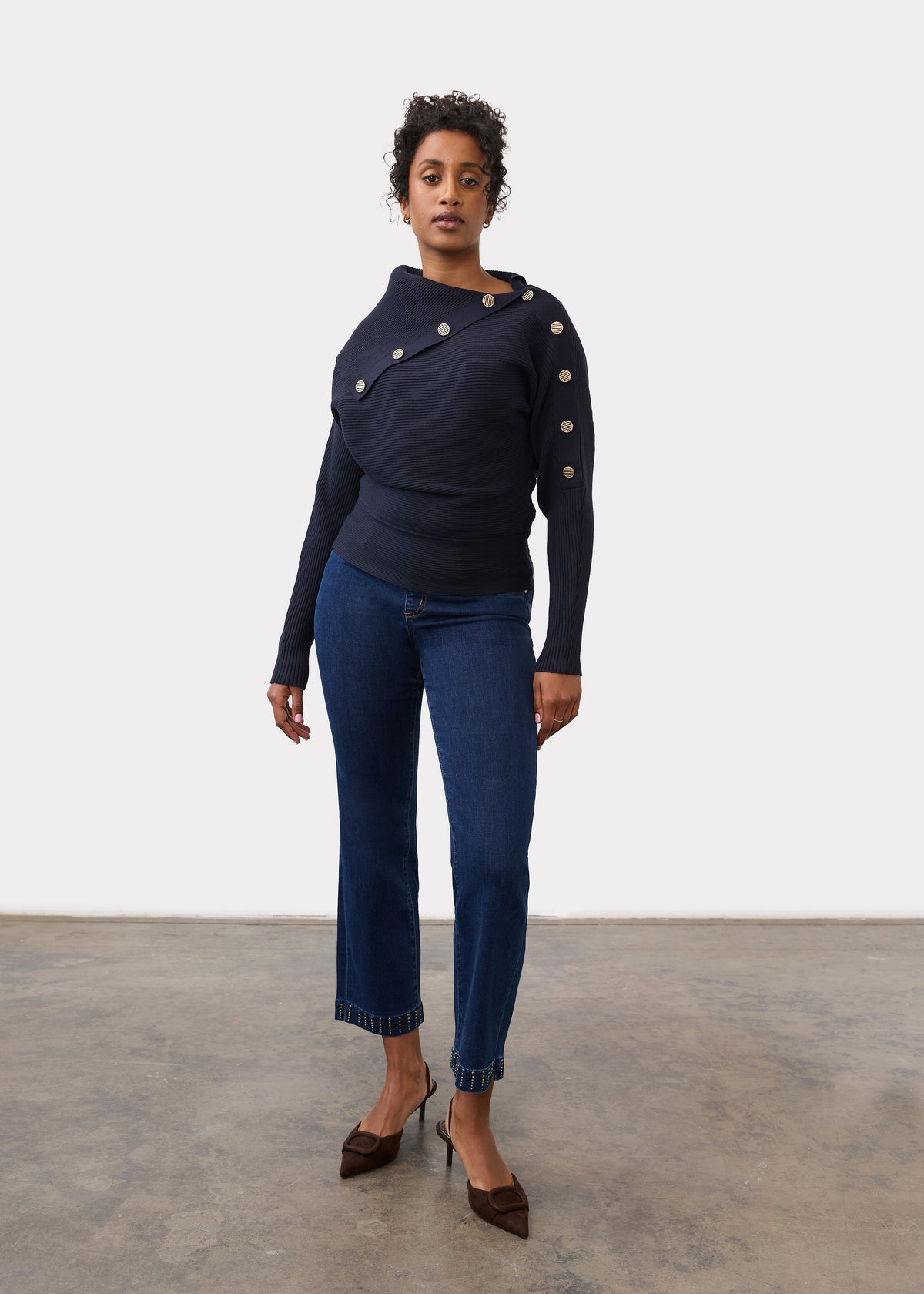 Full-length view of model in navy sweater with button details and blue jeans by French Dressing Jeans (FDJ)