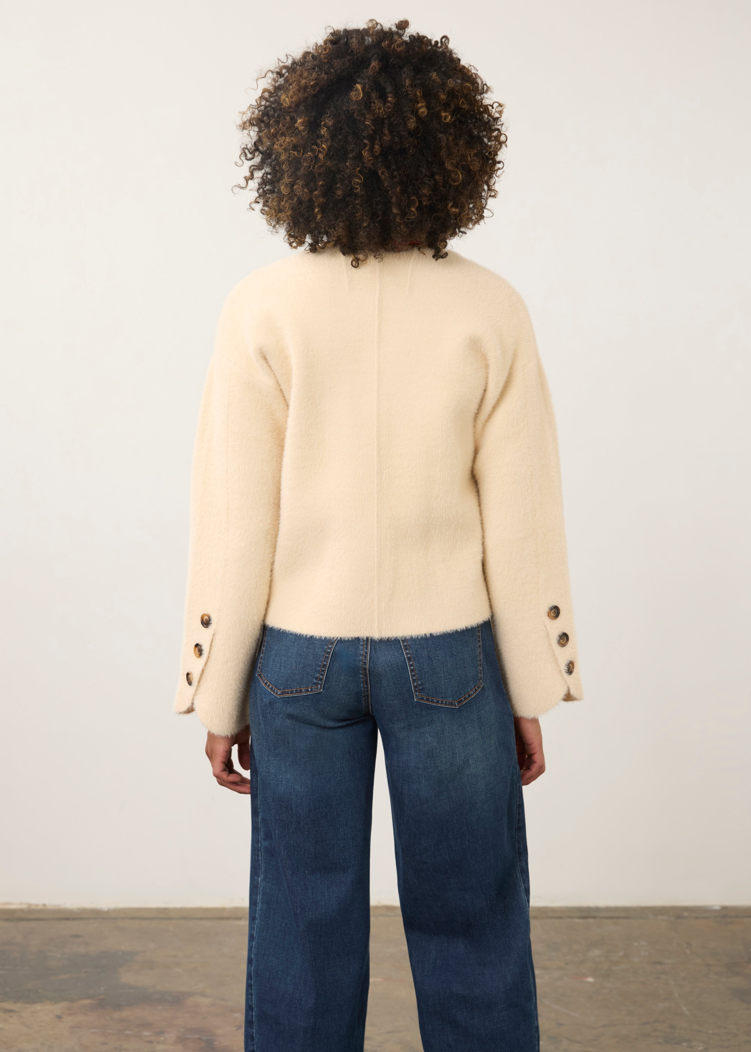 Back view of cream knit cardigan showcasing buttoned cuffs and straight hem by French Dressing Jeans (FDJ)