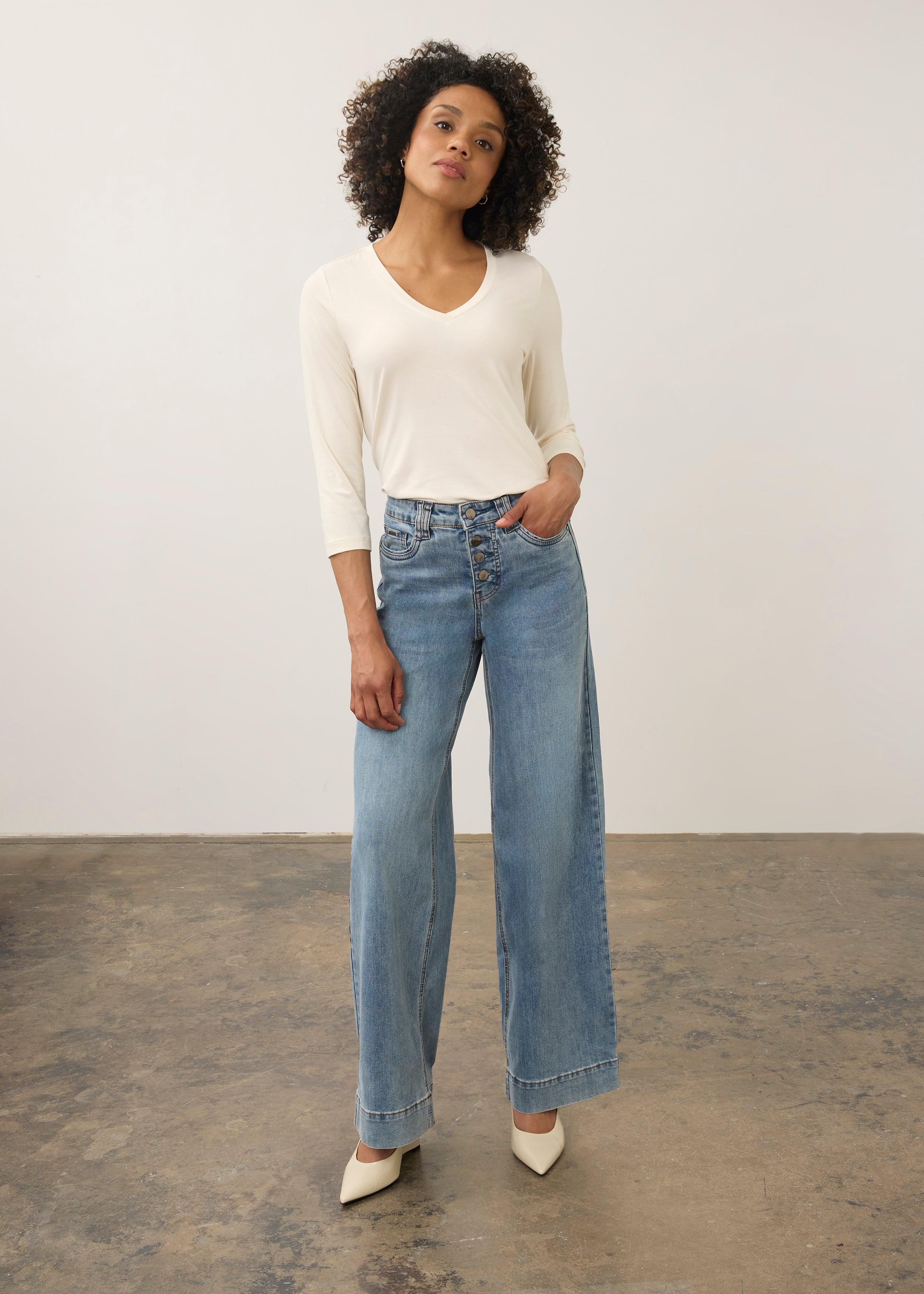 Full body view of cream V-neck top with relaxed fit and paired with high-waist jeans by French Dressing Jeans (FDJ)