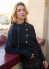 Model leaning on railing in navy sweater with button detail, looking away by French Dressing Jeans (FDJ)