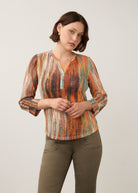 Front view of 3/4 sleeve Henley top in Heat color, button-front placket, paired with olive pants by French Dressing Jeans (FDJ)
