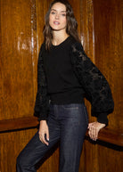 Front view of black sweater with velvet cut-out sleeves and floral lace details by French Dressing Jeans (FDJ)