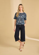 Full body view of blue Polynesian block print top paired with black pants and sandals by French Dressing Jeans (FDJ)