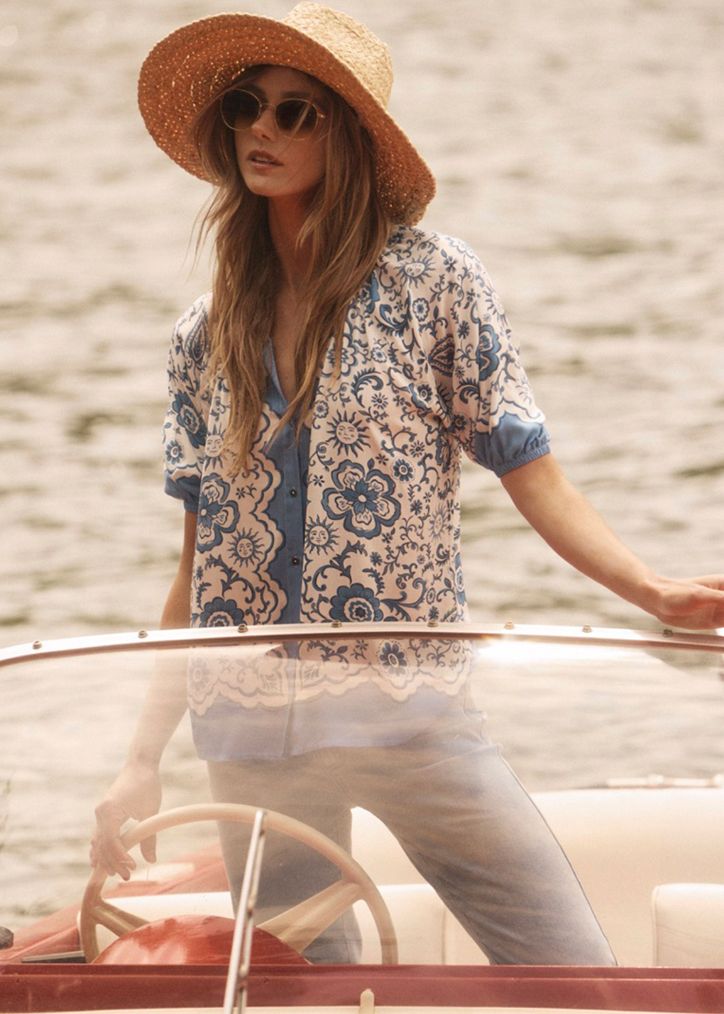 Model wearing Sundial printed shirt with blue floral pattern, steering a boat by French Dressing Jeans (FDJ)