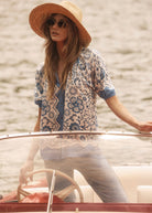 Model wearing Sundial printed shirt with blue floral pattern, steering a boat by French Dressing Jeans (FDJ)
