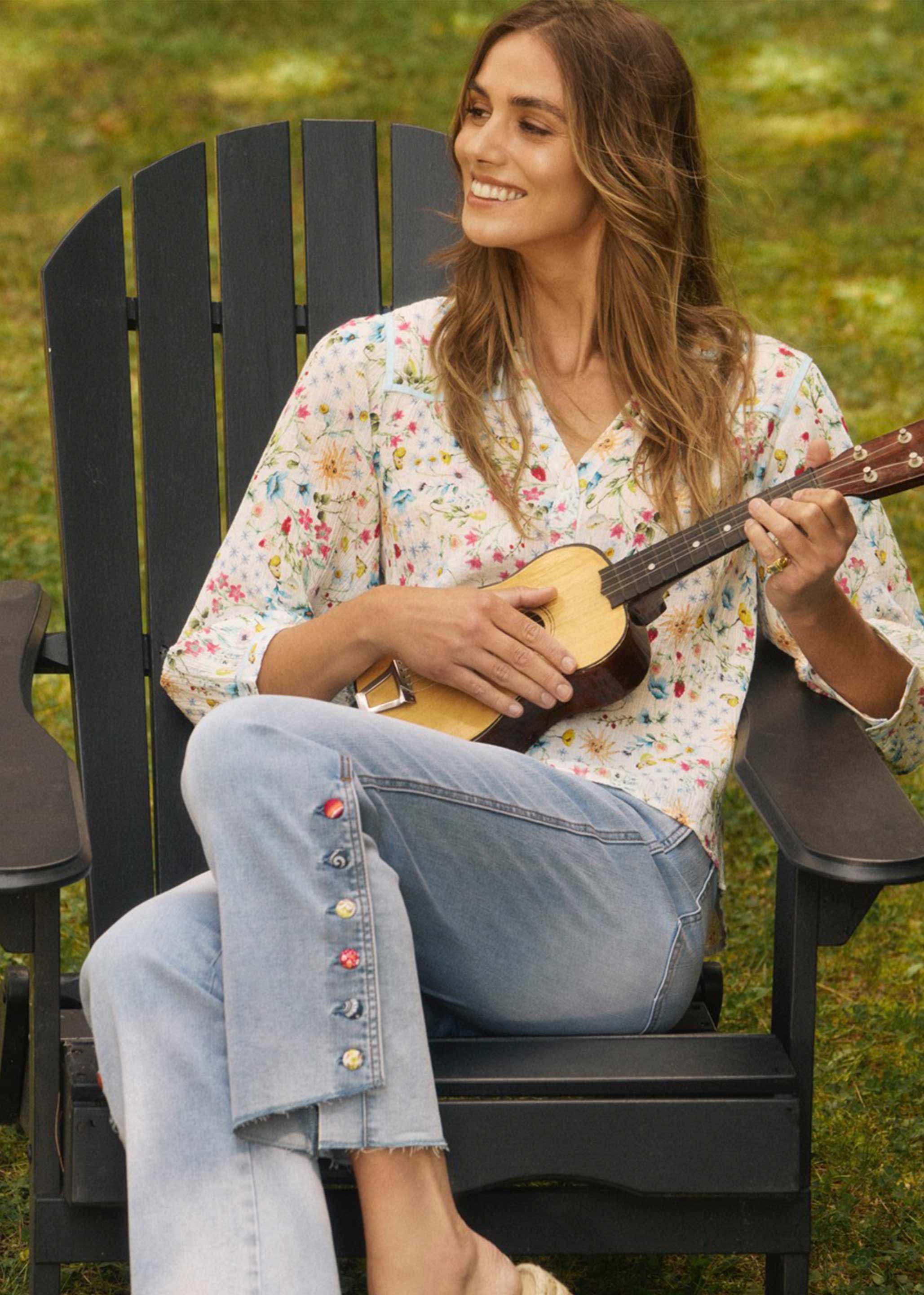 Model sitting, wearing blue eclipse pull-on boot crop denim with decorative buttons by French Dressing Jeans (FDJ)