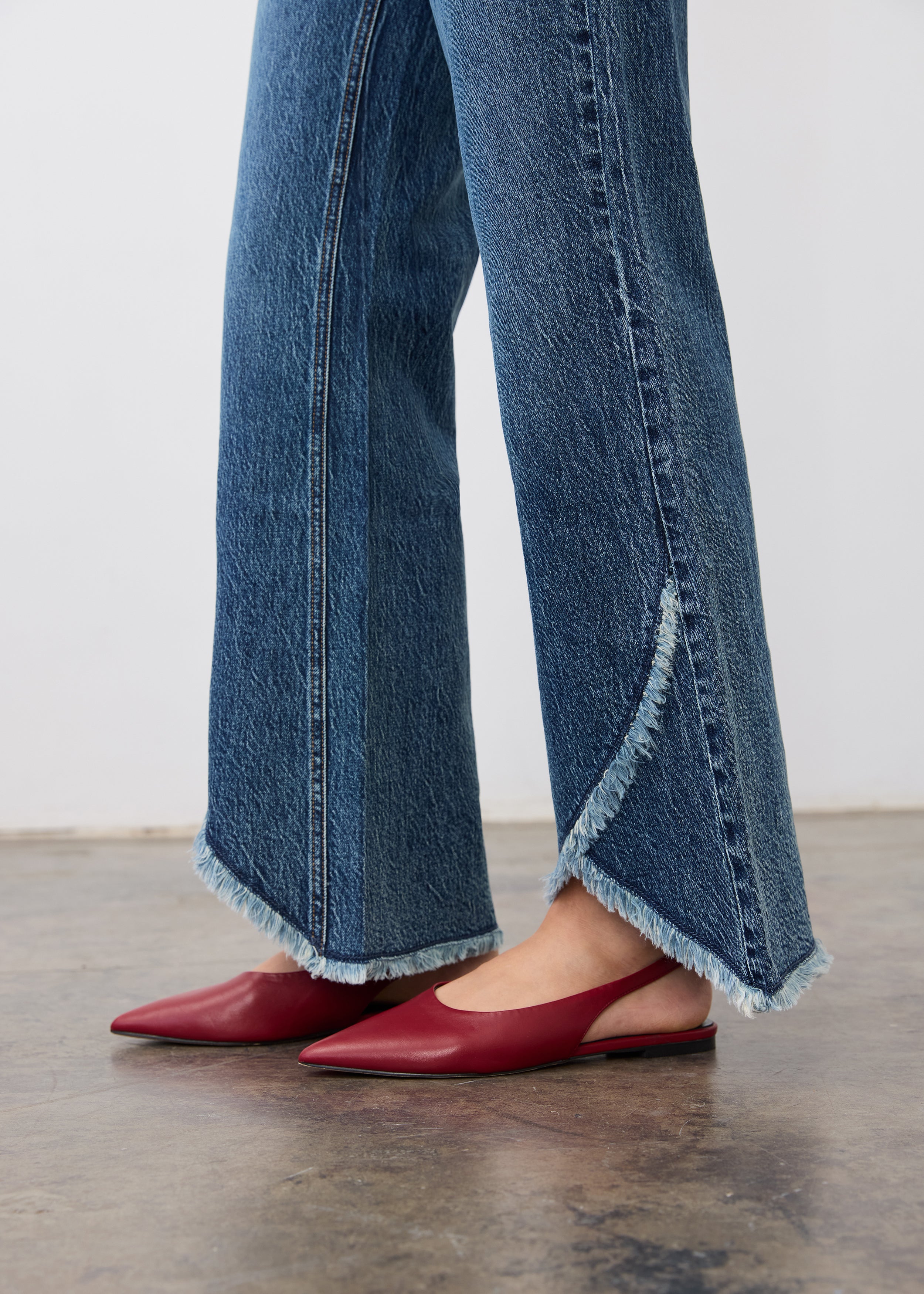 Side view highlighting tulip hem and fringe detailing on medium blue bootleg jeans by French Dressing Jeans (FDJ)