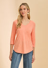 Front view of coral V-neck 3/4 sleeve top with a curved hem paired with denim by French Dressing Jeans (FDJ)