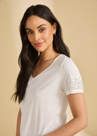 Close-up side view of white V-neck top highlighting pearl details on sleeves by French Dressing Jeans (FDJ)